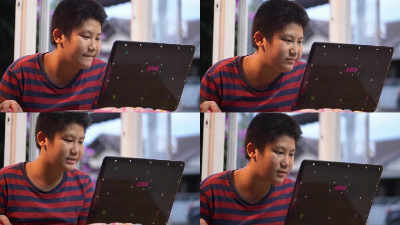 快乐的亚洲男孩在家里玩笔记本电脑在线比赛的游戏，生活方式的概念。
