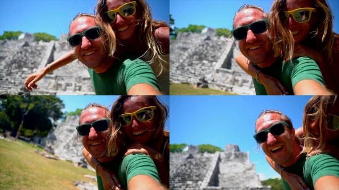 夫妇背着与墨西哥古代玛雅神庙自拍，人们旅行视点概念。两个人在移动设备上建立联系并共享视频聊天自拍照。