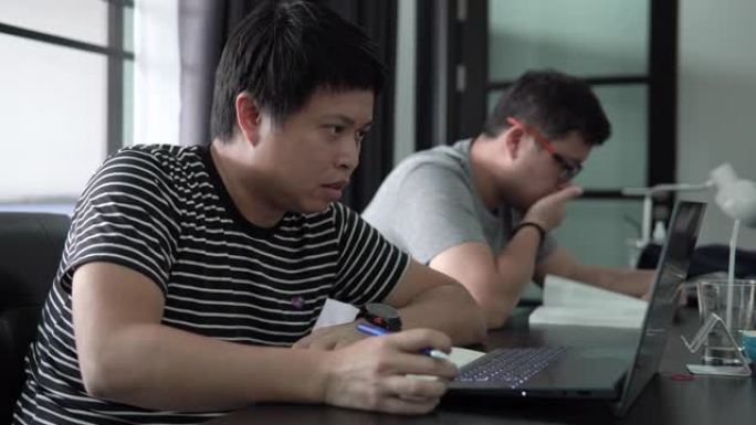 亚洲男子在家用笔记本电脑在线学习。