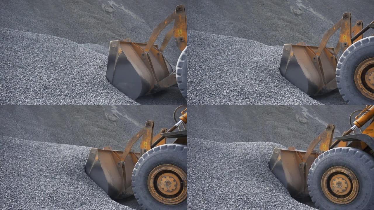 拖拉机收集一个装有砾石的勺子。库存镜头。挖掘机在施工现场用碎石或瓦砾装载铲斗的侧视图
