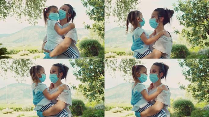 冠状病毒流行期间，蒙面母亲手握可爱的孩子。妈妈拥抱女儿，戴着医用口罩。慢动作镜头
