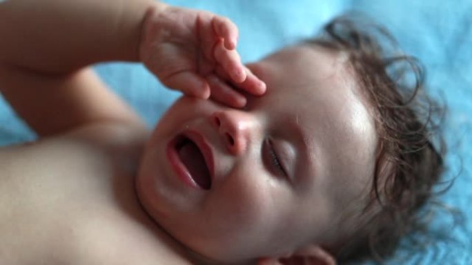 疲倦的婴儿用手揉眼睛。一岁的小孩想睡觉