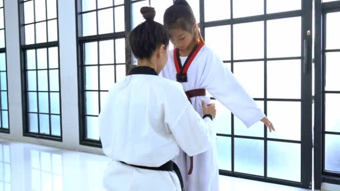 教练帮助女孩调整跆拳道的训练服装