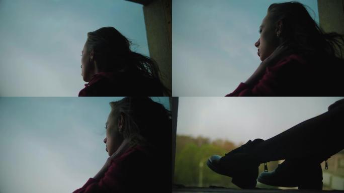 年轻漂亮的女孩坐在窗户上，想着，风吹着她的头发和衣服。