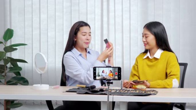 两名亚洲女性博客的4k视频片段录制vlog视频教程，并在社交媒体直播上评论推广带化妆化妆品的产品