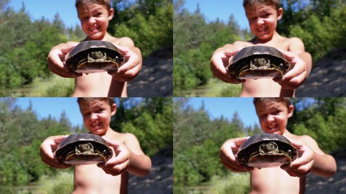 男孩抱着乌龟，在绿色植被的河上恶毒地微笑