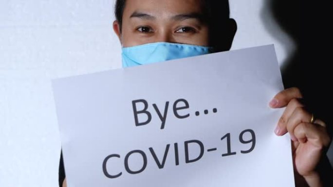 光线照耀着亚洲女人，拿着一张标有Bye COVID 19的纸，脱下卫生面膜，保护白色背景上的病毒。为