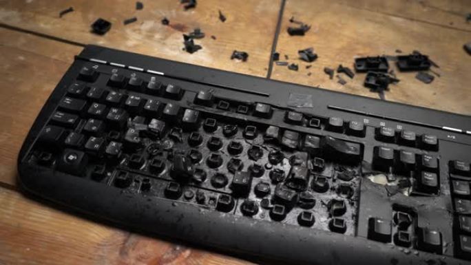 电脑桌上的键盘坏了。愤怒的男子用锤子砸键盘