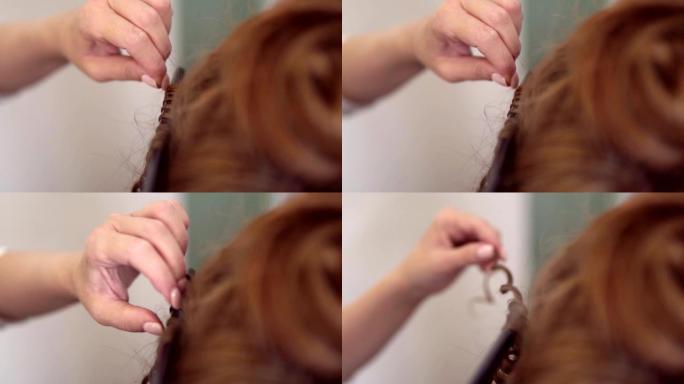一个红头女人在工作室里卷曲头发的特写镜头。美发用卷发器。无法辨认