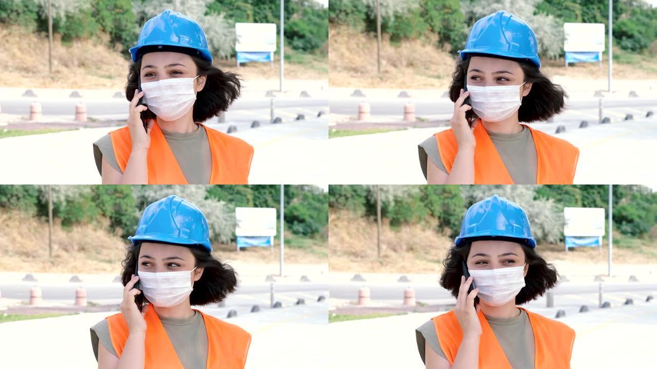一位可爱的年轻女性工程师或工人的肖像，穿着制服和保护性的蓝色头盔在施工现场打电话。4k分辨率，慢动作
