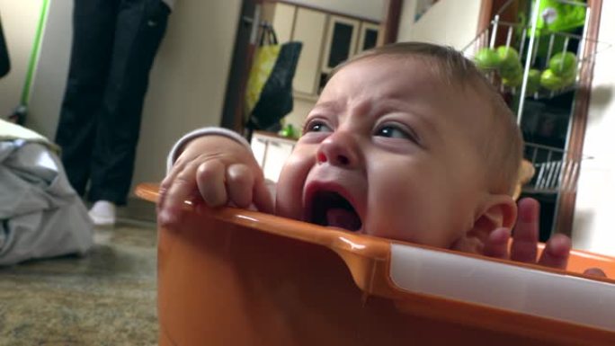 洗衣桶里有趣的心烦意乱的婴儿。愤怒的含泪的蹒跚学步的男孩想要关注