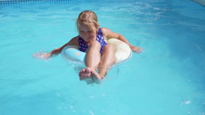 小女孩正在酒店游泳池休息。漂浮在橡胶圈上，微笑着。大热天游泳。