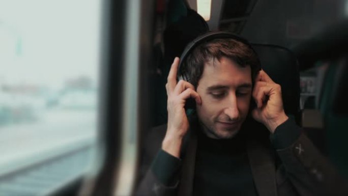 乘客在乘坐火车时摘下耳机并向窗外看