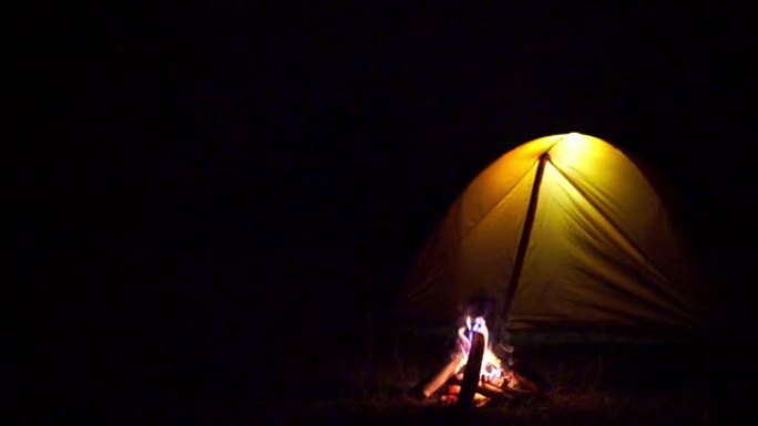自然游客正在黄色帐篷旁生火取暖。