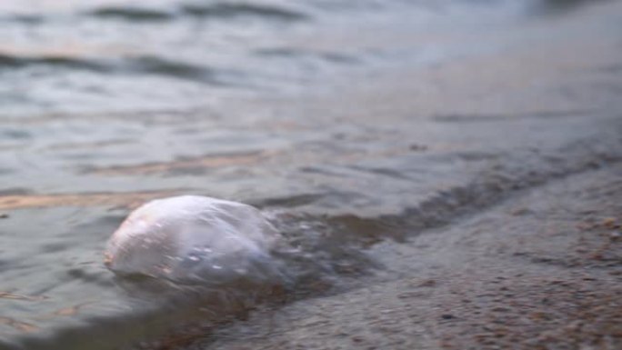 塑料袋漂浮在海水中，在沙质底部被波浪冲刷，靠近。自然破坏，全球环境污染问题。对真正的消费生态的需求