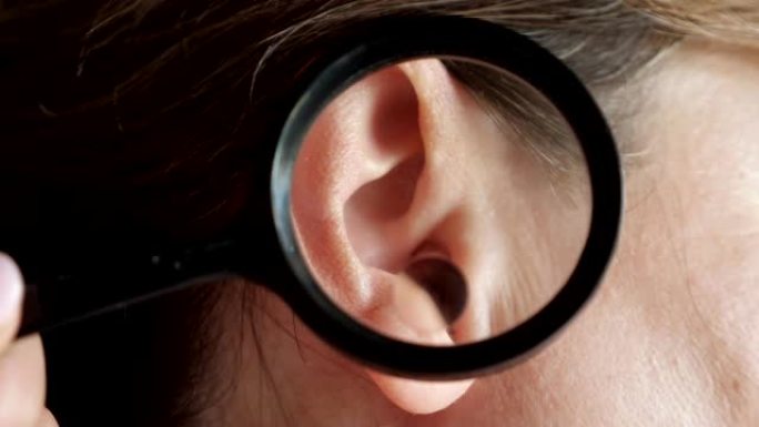 皮肤科医生使用放大镜检查患者耳朵中的大痣
