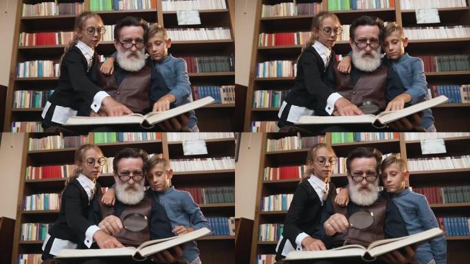 感兴趣的祖父和他的孙子们的全家福，他们坐在书架旁，有很多书，用放大镜读厚书