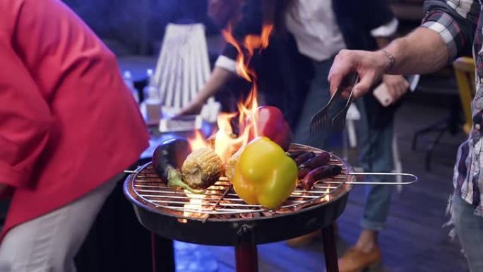 英俊的男人正在户外烧烤派对上为他的朋友烧烤美味的食物。野餐时间，周末