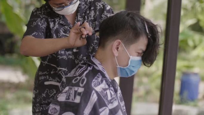 年轻男性被戴着防护面具的理发师染发。