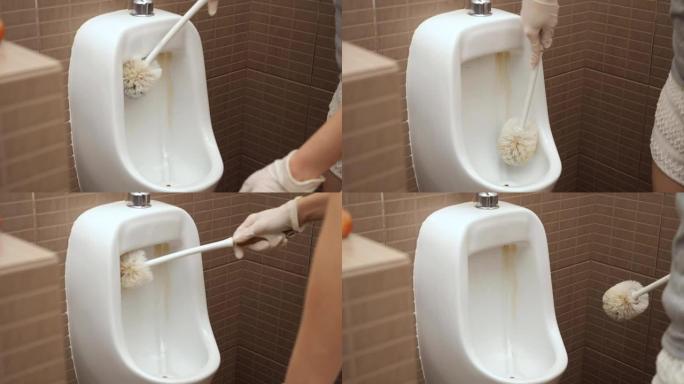 妇女用刷子戴上手套清洁小便池碗。