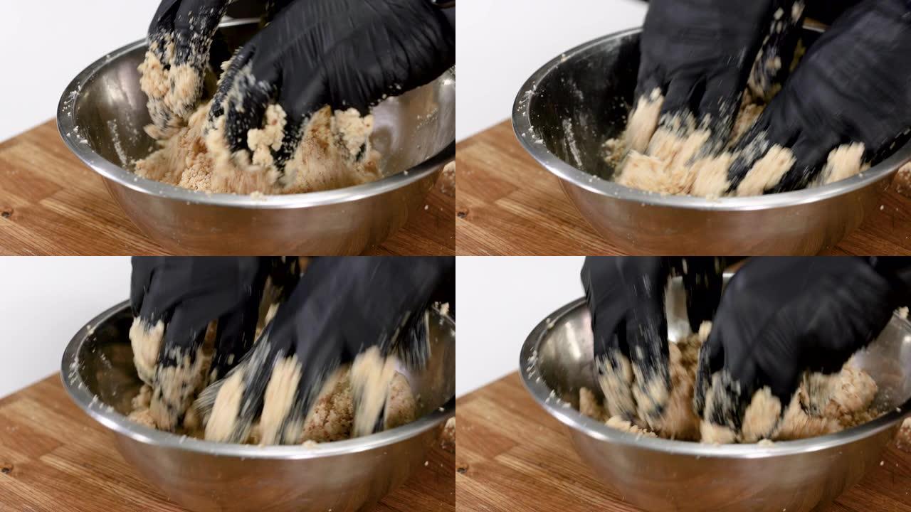 男人戴着黑色手套的手在碗里搅拌磨碎的饼干和黄油。4K