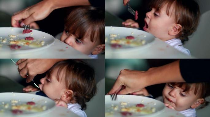 喂养靠在桌子上的可爱宝宝。父母喂养一岁的蹒跚学步的男孩