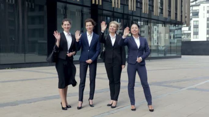 微笑着专业公司办公室商务女团队成员组看着镜头，四名快乐自豪自信的领导员工员工组人员组站在一起，挥手告