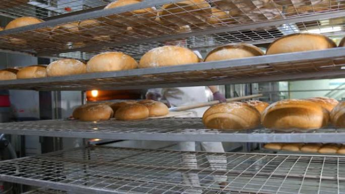 厨师从烤箱中取出新鲜出炉的烘焙产品。将烤面包从面包店的烤箱中取出。