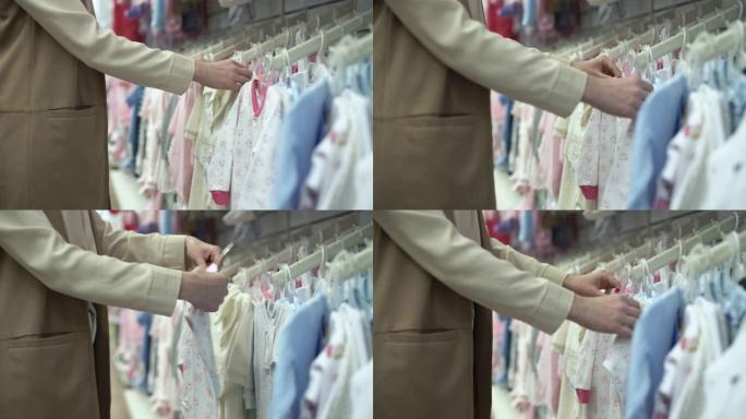 父母，快乐的年轻女人买家为她的孩子选择衣服妈妈在商店选择高品质的童装，特写
