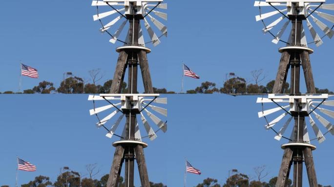 经典的复古风车，叶片转子和美国国旗对抗蓝天。老式水泵风力涡轮机，牲畜牧场或农业农场的发电机。狂野西部