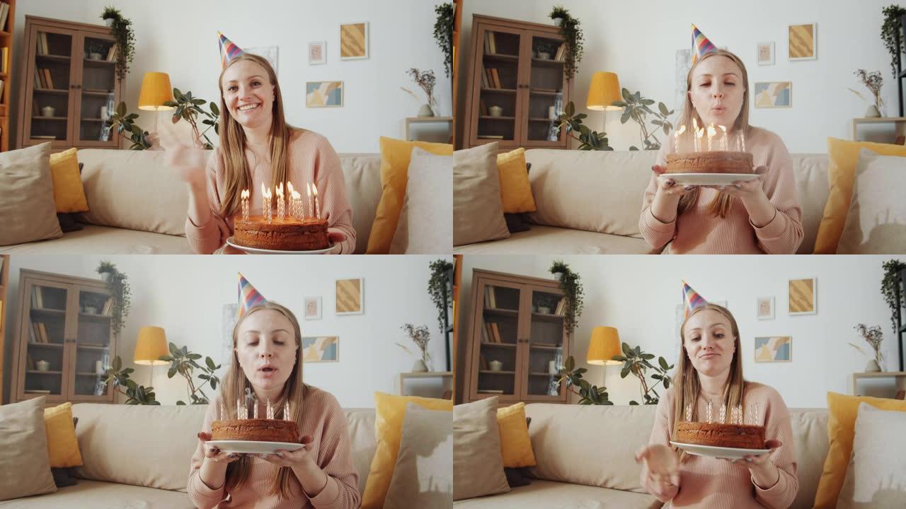 快乐的女人在网上庆祝生日时在蛋糕上吹蜡烛