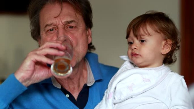 祖父母抱着孙子婴儿时喝啤酒。爷爷和孙子在一起