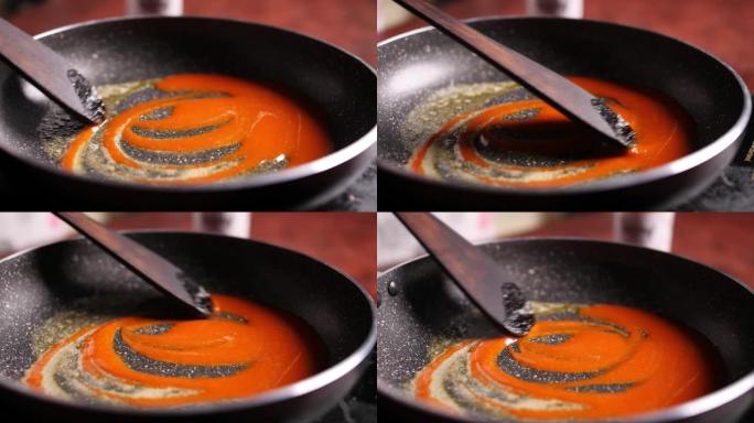 红酱和黄油的慢动作特写镜头用木铲在锅中缓慢搅拌