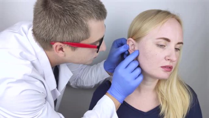耳鼻喉科医生检查一个抱怨疼痛的女孩的耳朵。疼痛缓解和治疗理念。耳道或鼓膜炎症