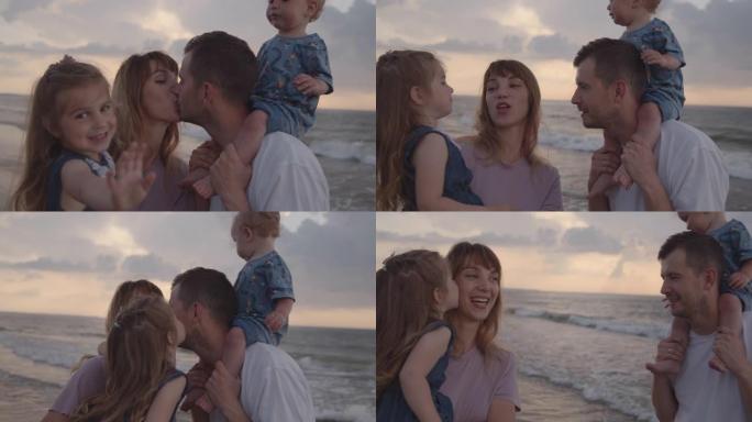 年轻的父母站在海边，抱着他们的小孩，亲吻
