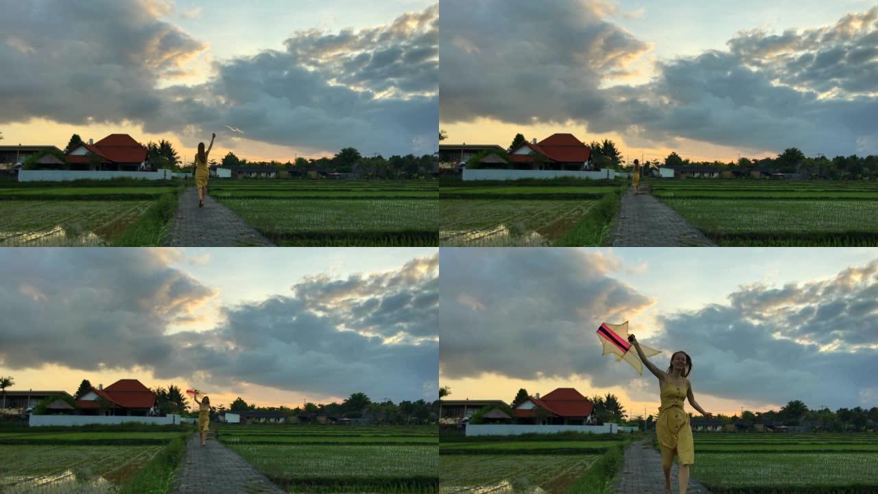 一个年轻女子在美丽的稻田上放风筝奔跑。在电话上拍摄