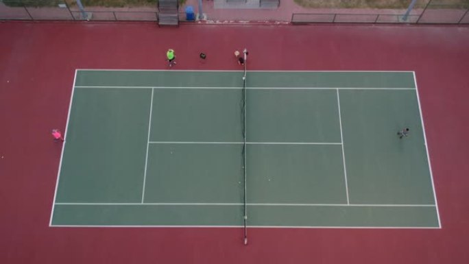 女孩和男孩正在打网球，他们的网球教练正在展示正手高清视频无人机视图