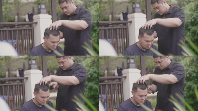 年轻的亚洲男性在家剪头发。