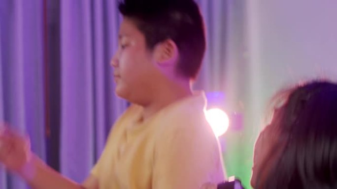 快乐的亚洲孩子在晚上用彩色发光二极管灯在家一起跳舞，生活方式理念。
