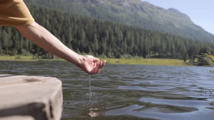 人的手托着从高山湖中捕捉淡水，夏日光明。在瑞士拍摄