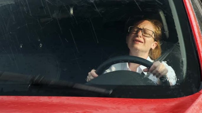 沮丧的女商人哭着开车，窗外下雨