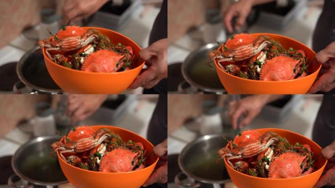 厨师从锅中取出煮熟的红蓝蟹，将它们折叠成一个橙色的碗。