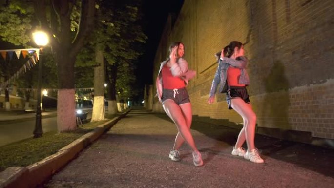 晚上，两个年轻女子在城市公园跳街舞。青年亚文化。当代舞蹈。万向节射击