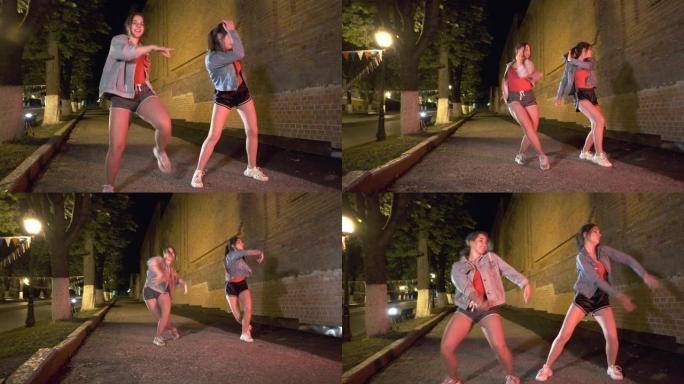 晚上，两个年轻女子在城市公园跳街舞。青年亚文化。当代舞蹈。万向节射击