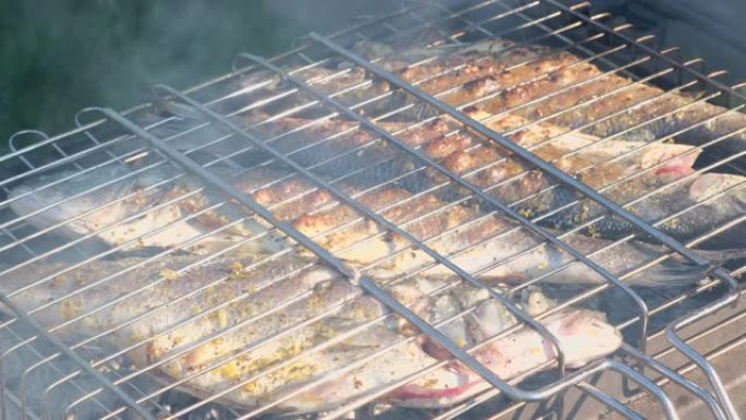 用木炭烤的鲈鱼或石斑鱼。在烧烤烤架板上用芳香香料烹饪海鱼的特写镜头