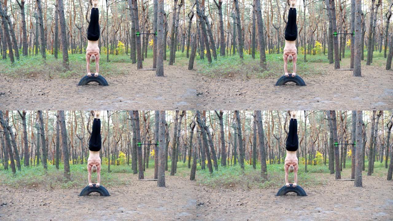 肌肉发达的人在森林里训练倒立。强壮的体操运动员在自然环境中锻炼。运动员在户外展示瑜伽练习。健康积极生