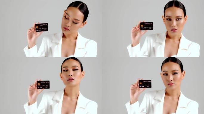 美丽的亚洲女商人出示信用卡并看着相机