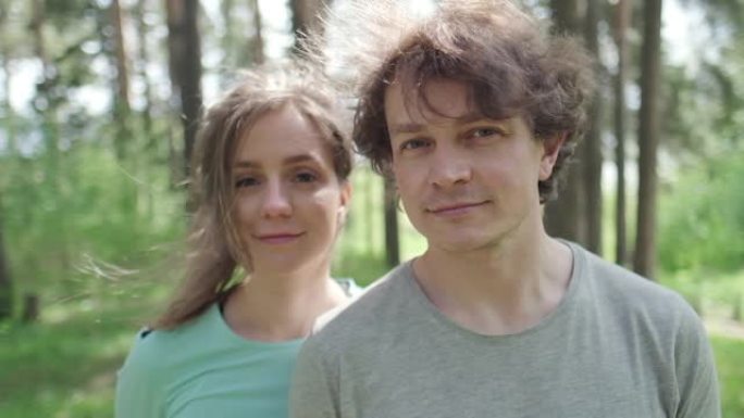 年轻夫妇站在户外阳光明媚的森林中的肖像。轨道摄像机