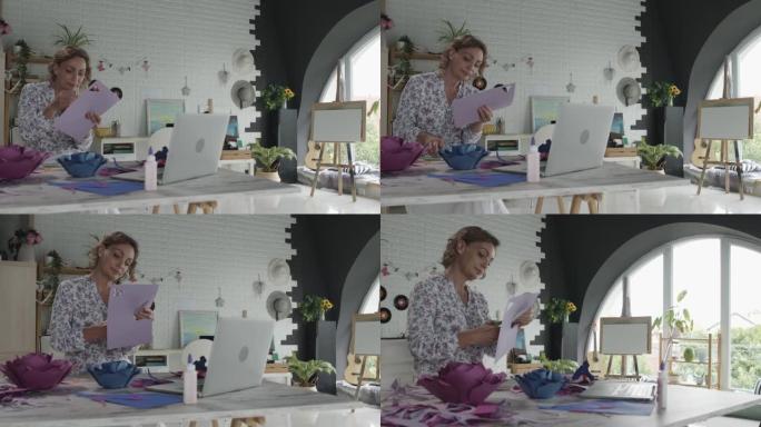 女人在为花朵制作花瓣时切割工艺纸，她正在制作