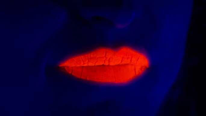 年轻女子在紫外线下涂红嘴唇